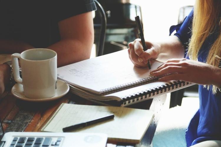 A woman writting on the notebook